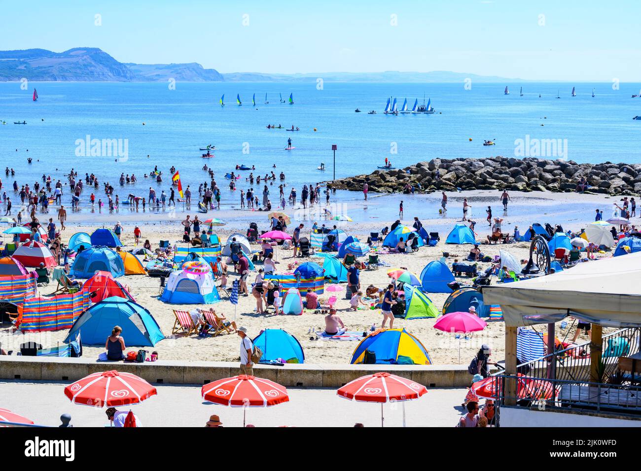 Lyme Regis, Dorset, UK. 29th July, 2022. UK Weather: Crowds of holidaymakers and sunbathers flock to the packed beach at the seaside resort of Lyme Regis to bask in scorching hot sunshine. Families, staycationers and sunseekers soaked up the lovely sunny weather as it made a welcome return in time for the weekend. Credit: Celia McMahon/Alamy Live News Stock Photo