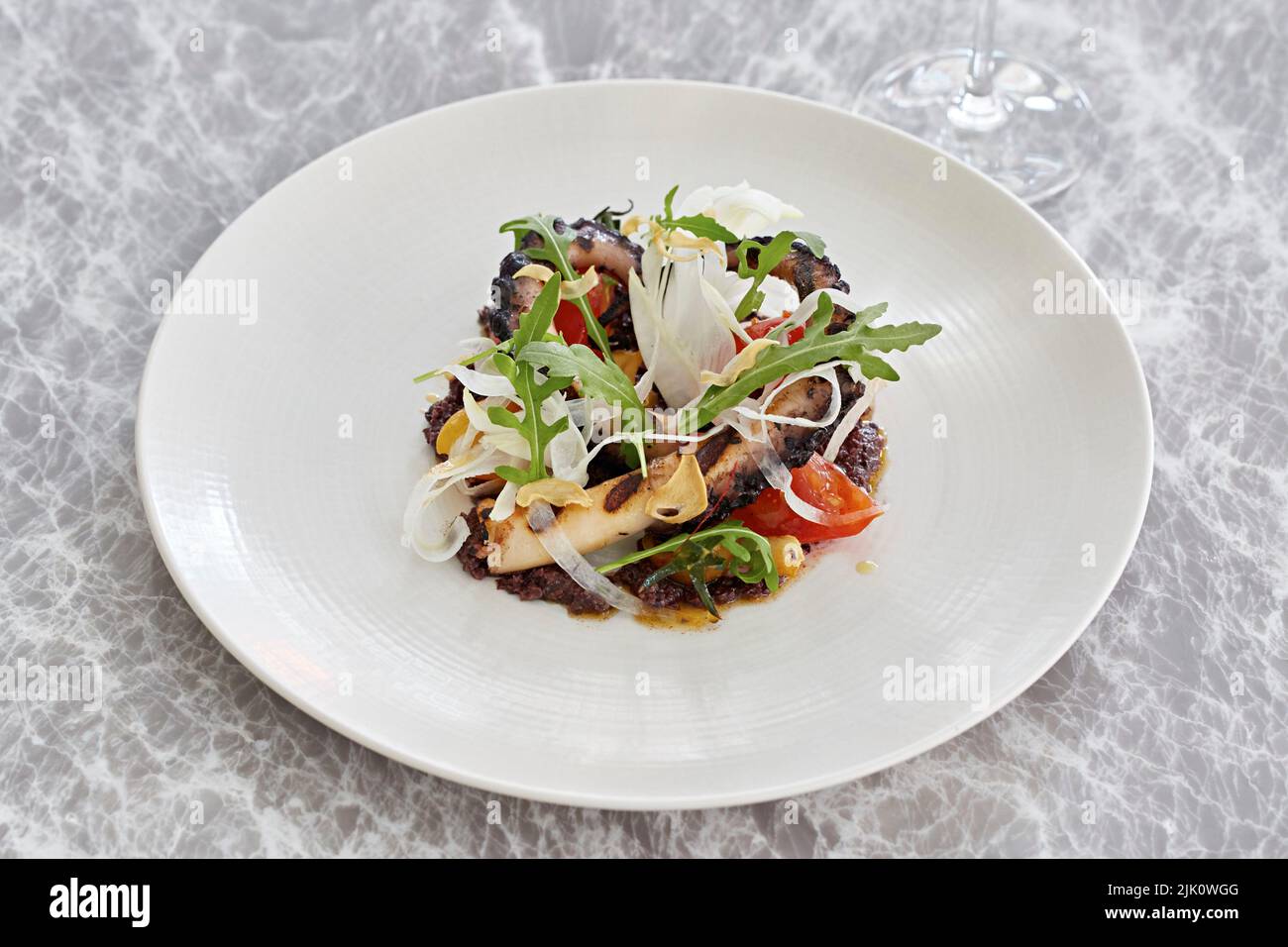 Octopus, fennel, tomato and rocket salad with fried garlic Stock Photo