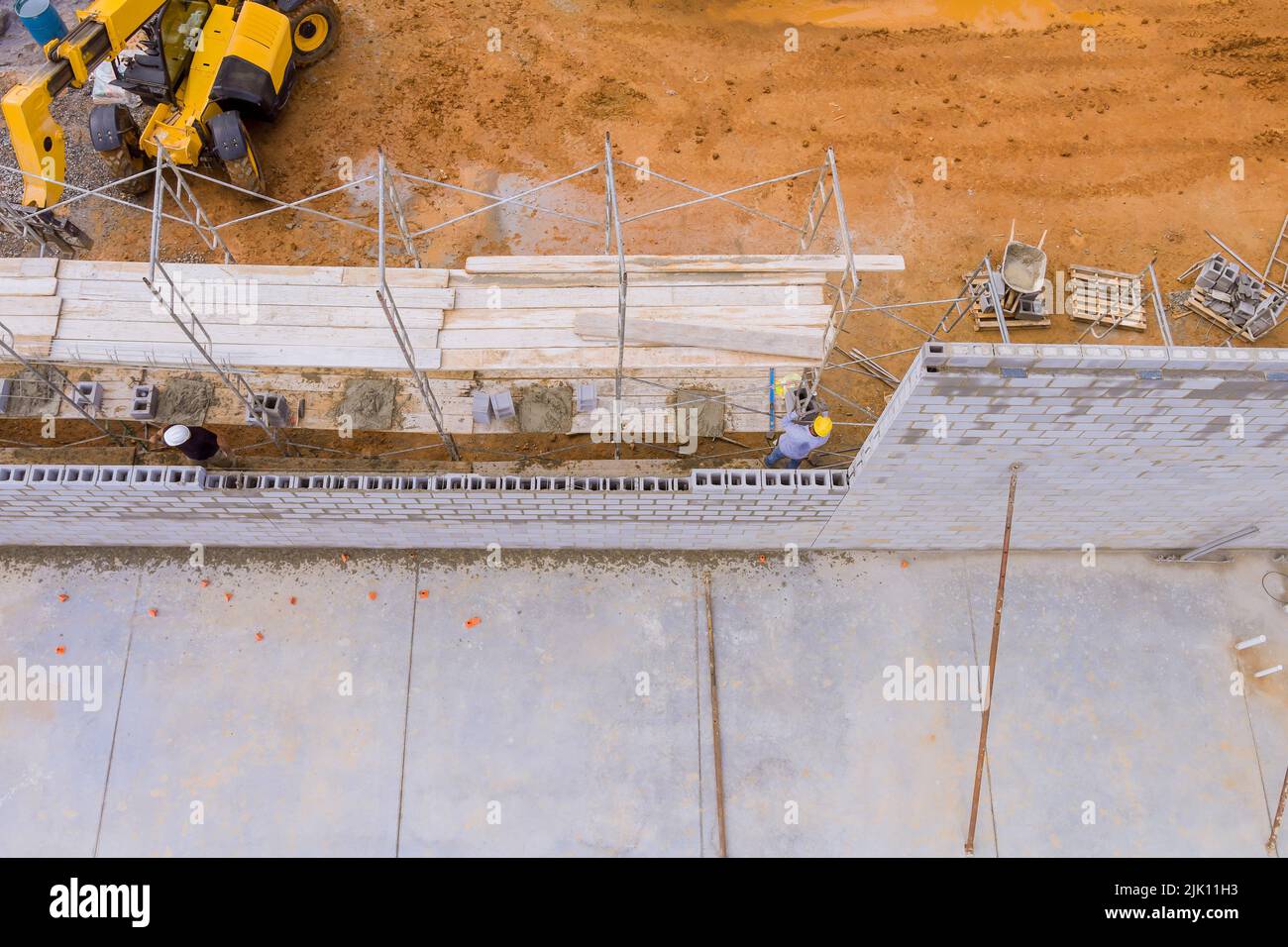 Scaffolding in the construction site, workers are seen laying bricks