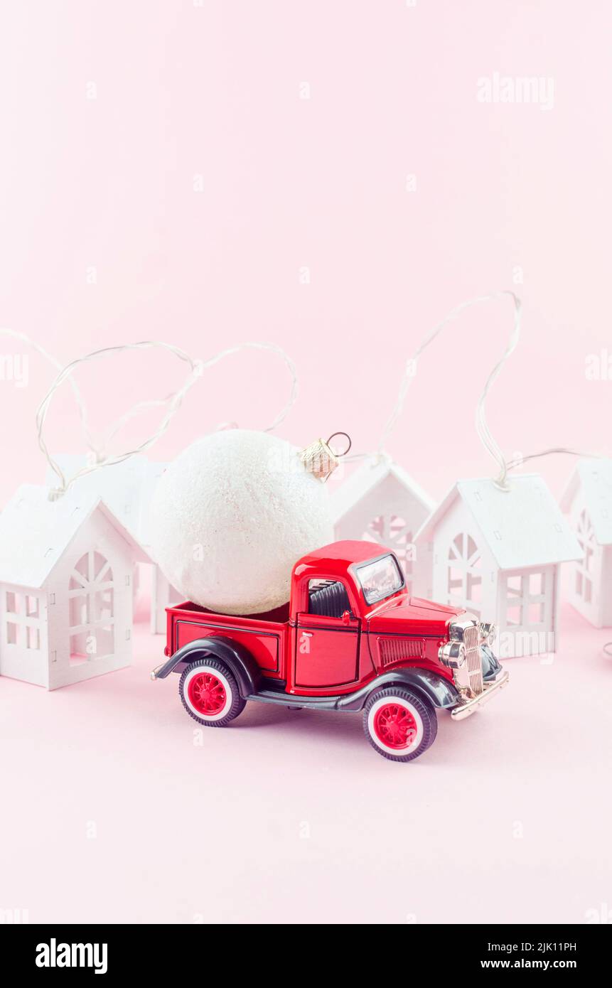 Red retro Pickup with Christmas decoration ball on pastel pink background. Merry Christmas holiday concept. copy space. Template of greeting card.Zapo Stock Photo