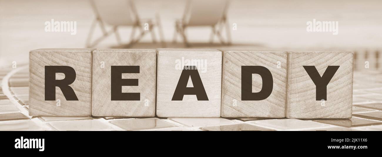 word ready made with wooden blocks standing on swimming pool border ...