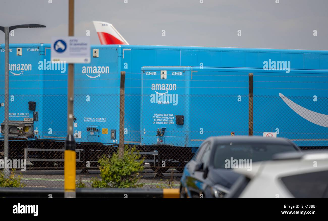 Heathrow Airport, London, UK. 28 July 2022. A line of blue Amazon roll door freight trailers parked inside the perimeter fence at Heathrow airport Stock Photo
