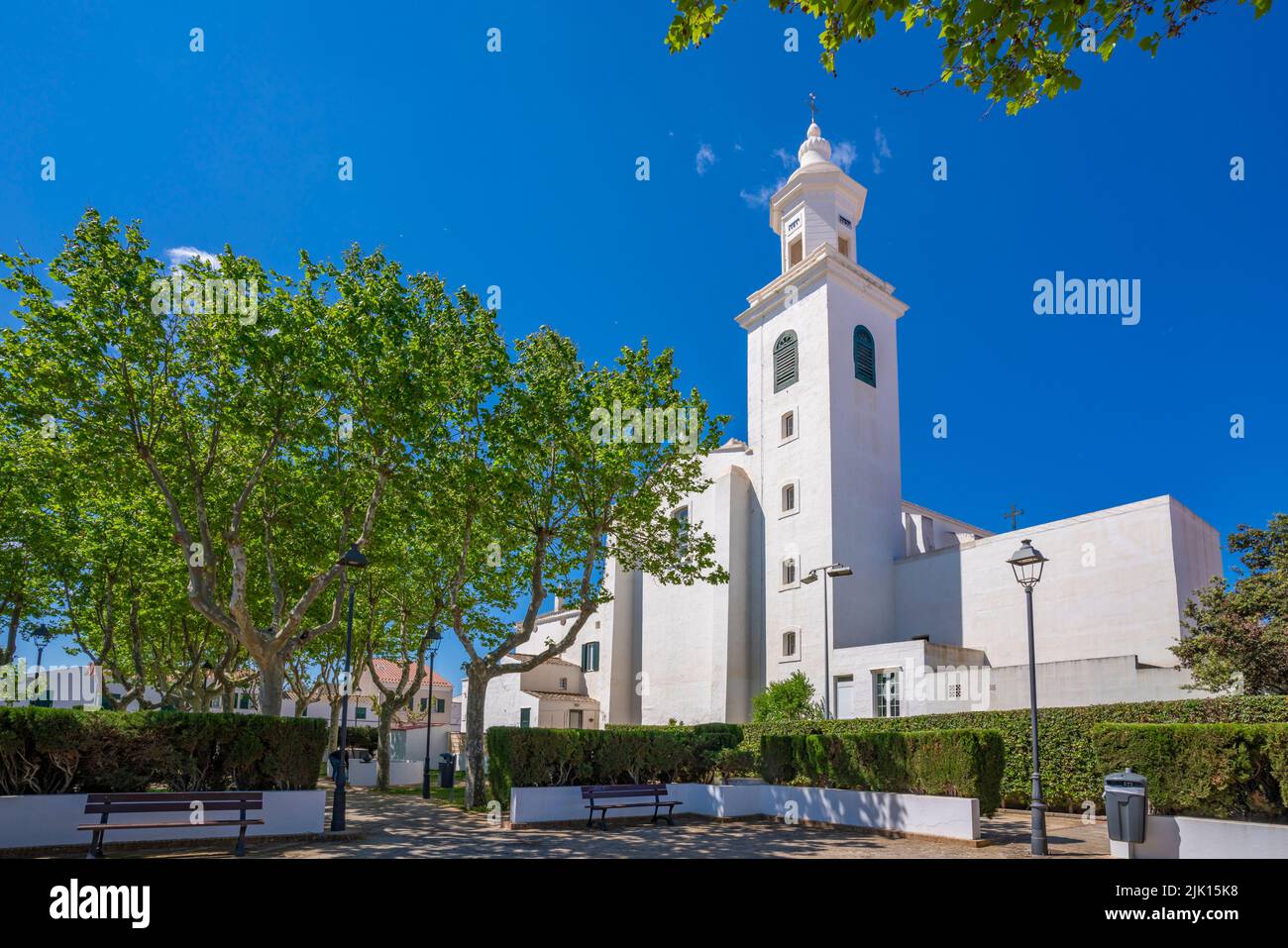 View of whitewashed Catholic Church framed by trees against blue sky, Sant Lluis, Menorca, Balearic Islands, Spain, Mediterranean, Europe Stock Photo