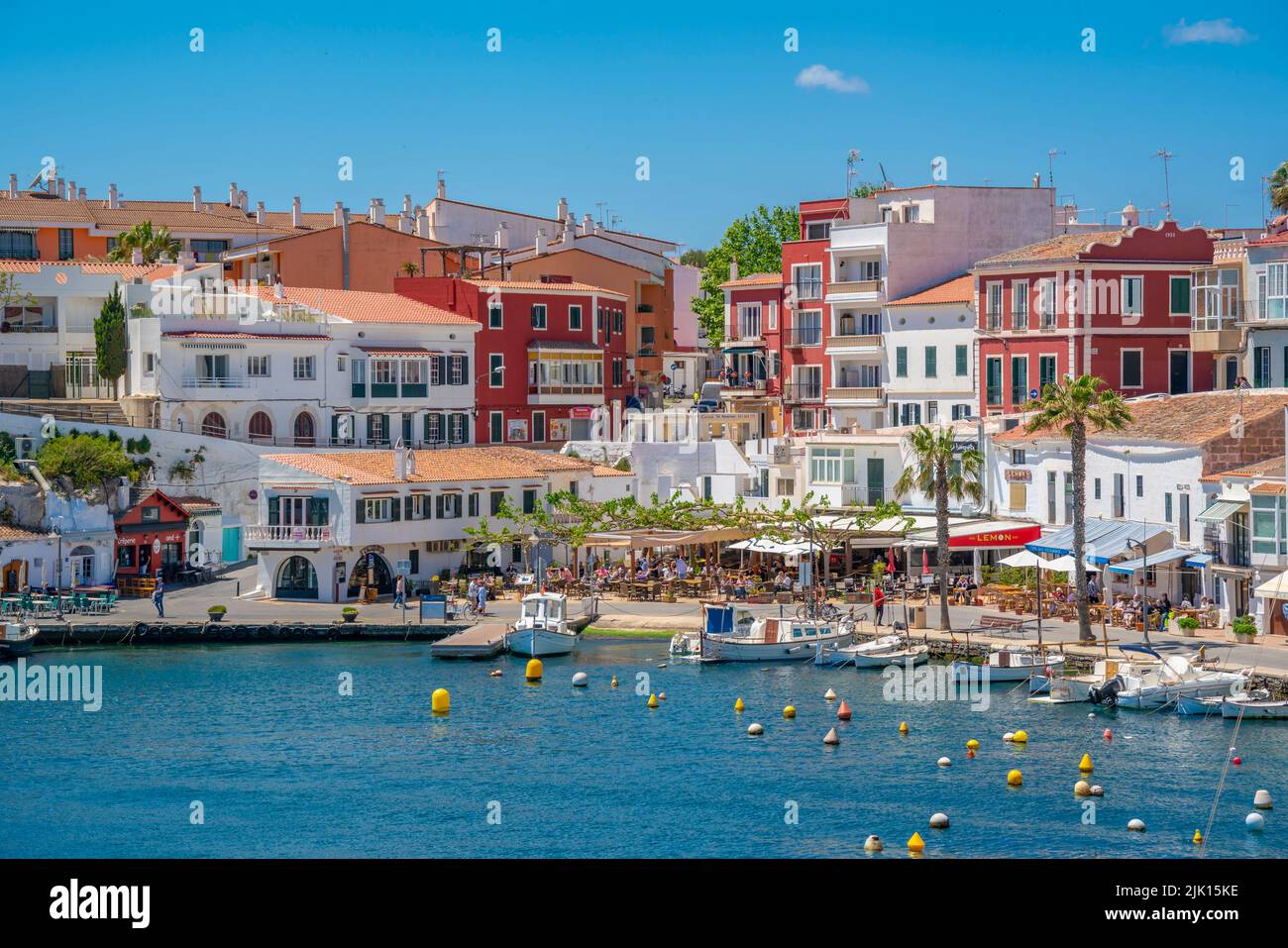 View of colourful cafes, restaurants and boats in harbour against blue sky, Cales Fonts, Menorca, Balearic Islands, Spain, Mediterranean, Europe Stock Photo