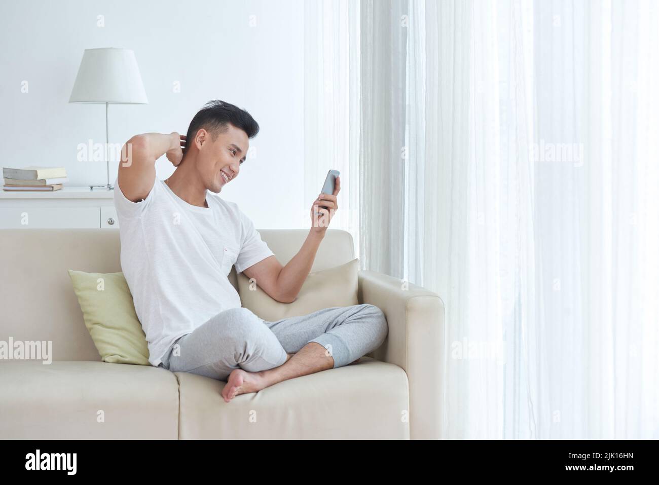 Handsome young man reading messages in his smartphone Stock Photo