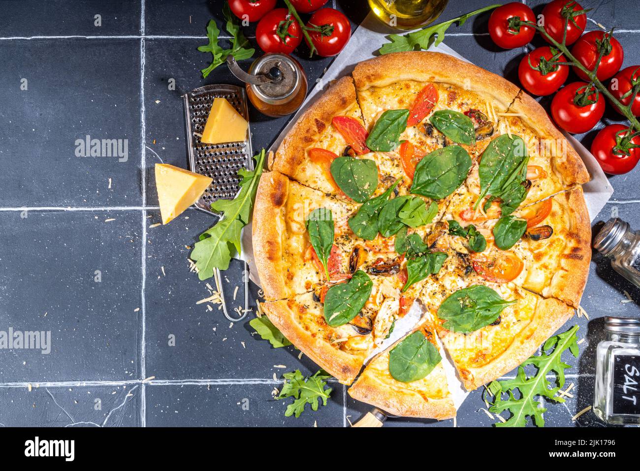 Three various pizzas, served at home or in restaurant on tiled table with cooking ingredients