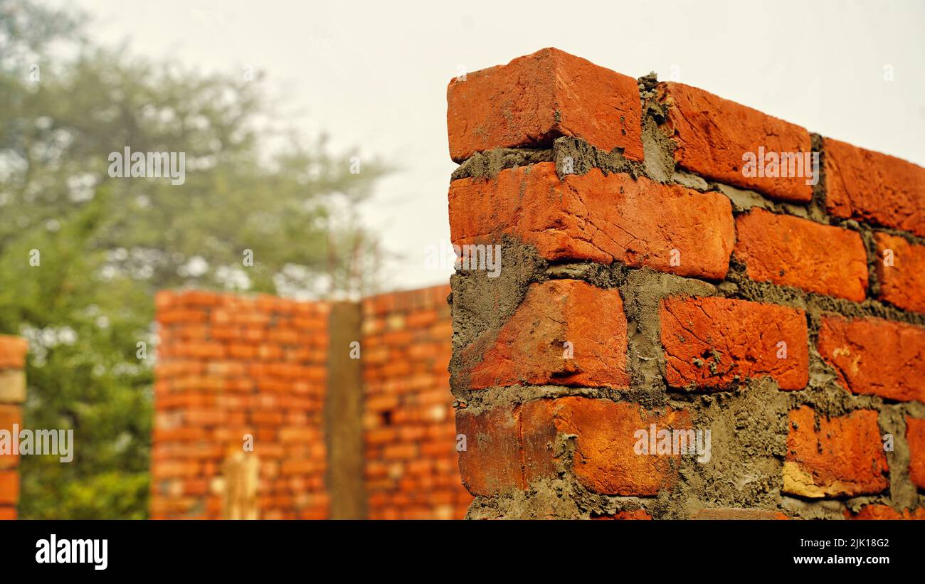Brick wall under construction on nature background. Red Brick Wall With Diminishing Perspective. Fragment of brown brick wall with a shallow depth of Stock Photo