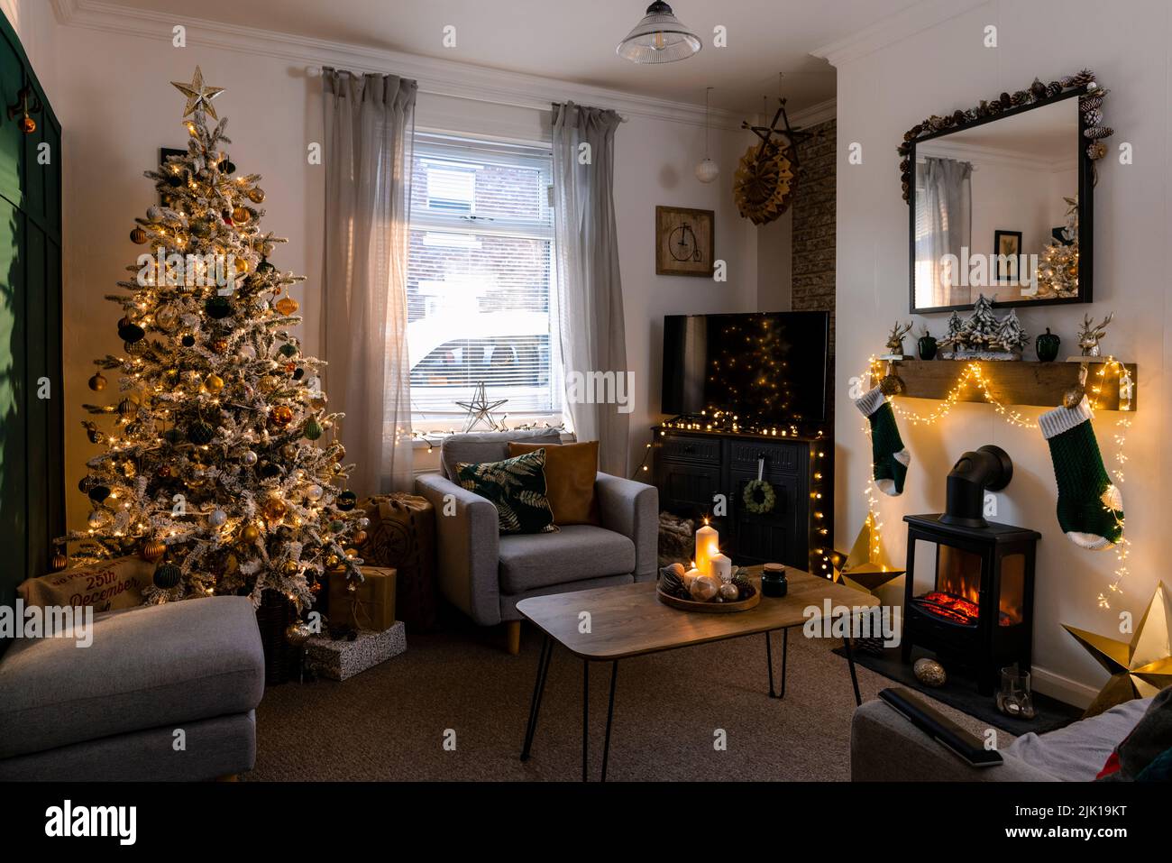 A wide shot of a Christmas tree decorated with golden-orange shiny balls and lights in a living room. Stock Photo