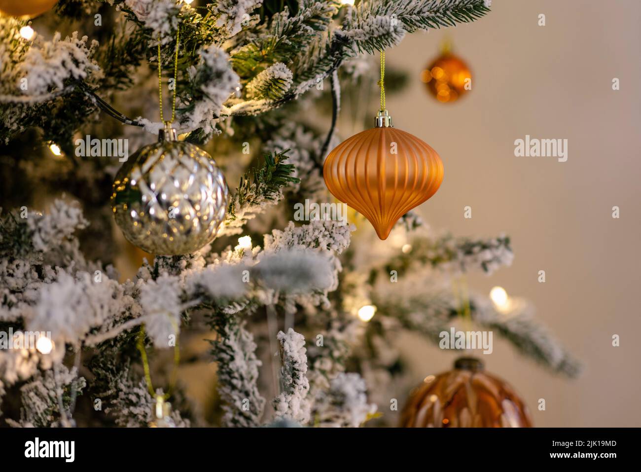 A close-up shot of a Christmas tree decorated with golden-orange shiny balls and lights. Stock Photo