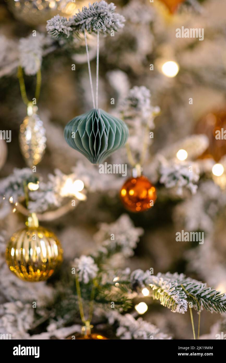 A close-up shot of a Christmas tree decorated with golden-orange shiny balls and lights. Stock Photo