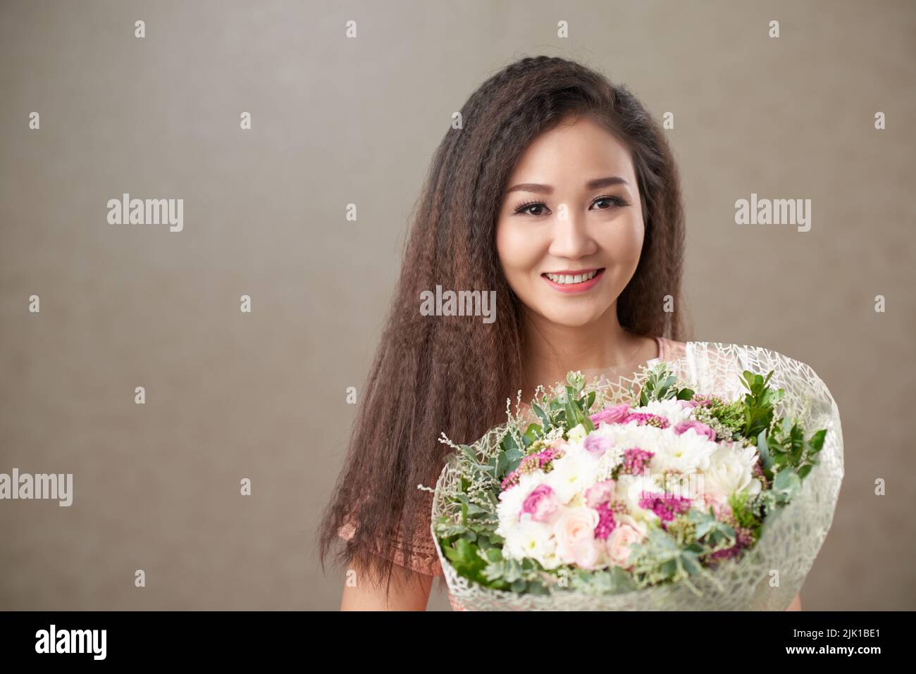 Smiling Asian woman holding bunch of flowers Stock Photo