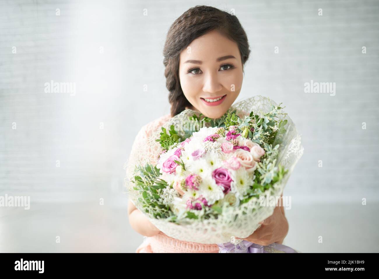 Attractive Asian young woman holding big beautiful bouquet Stock Photo
