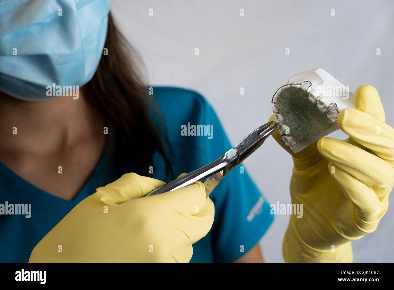 The woman dentist is holding dentures in his hands and instruments ...