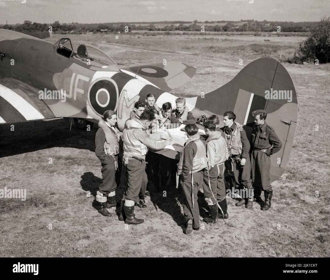 A pilot briefing on the elevator of a Hawker Tempest Mark V, 'JF-M' at Newchurch, Kent, prior to a sweep over the Caen area. The Hawker Tempest was a British fighter aircraft used by the Royal Air Force (RAF) used from 1944 in the Second World War. It was the fastest single-engine propeller-driven aircraft of the war at low altitude. It performed low-level interception, particularly against the V-1 flying bomb threat, and ground attack against rail infrastructure in Germany and Luftwaffe aircraft on the ground Stock Photo