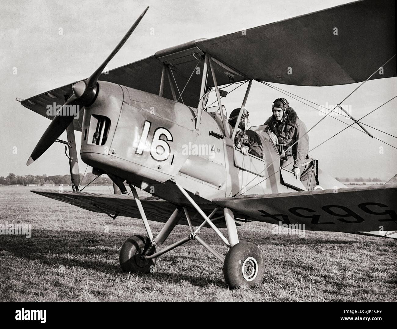 A trainee pilot and his instructor (in the front cockpit) preparing for a flight in a de Havilland Tiger Moth at an Elementary Flying Training School.The Tiger Moth was a 1930s British biplane designed by Geoffrey de Havilland and built by the de Havilland Aircraft Company. It was operated by the Royal Air Force (RAF) and other operators as a primary trainer aircraft Stock Photo