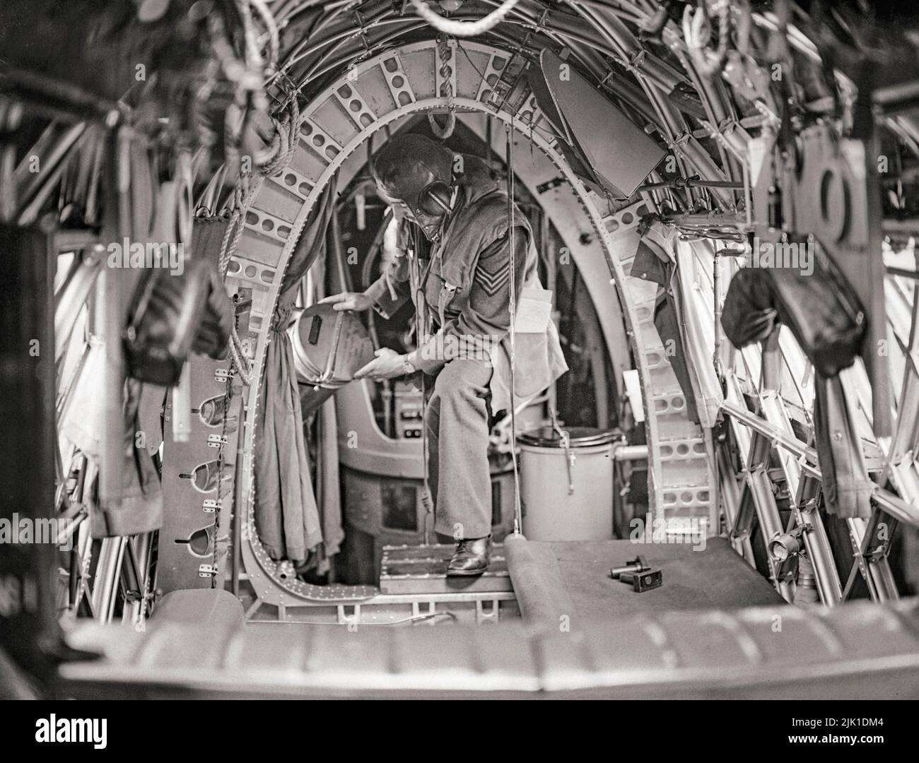 A crew member on board a Vickers Wellington of No. 75 (New Zealand) Squadron RAF places night flares in position in the cramped rear fuselage. The Wellington was a British twin-engined, long-range medium bomber designed in the mid-1930s used as a night bomber in the early years of the Second World War, performing as one of the principal bombers until superseded by the larger four-engined 'heavies' such as the Avro Lancaster. It holds the distinction of having been the only British bomber that was produced for the duration of the war. Stock Photo