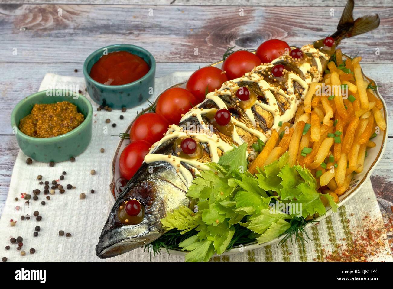 Fried mackerel fish with french fries, tomatoes and celery leaves
