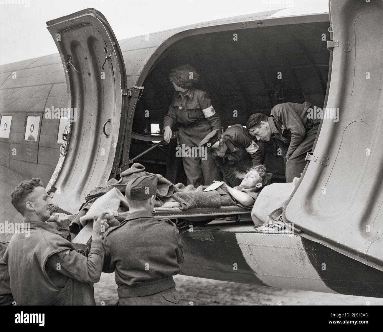 Aircrew and WAAF nursing orderlies help to load a battle casualty on a stretcher into a Douglas Dakota Mark III of No. 233 Squadron RAF. The RAF's first 'casevac' flights to France were mounted by Dakotas of No. 46 Group on 13 June 1944, and the WAAF nursing orderlies were the first women to be employed on these duties'. Stock Photo