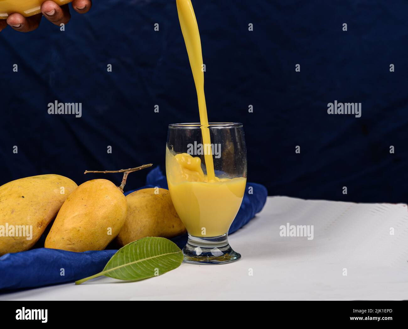 Glass of fresh and yummy mango milkshake pouring in glass. Stock Photo