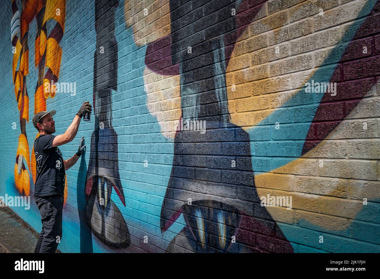 Graffitist Super A putting the finishing touches to a mural in Leicester. Stock Photo