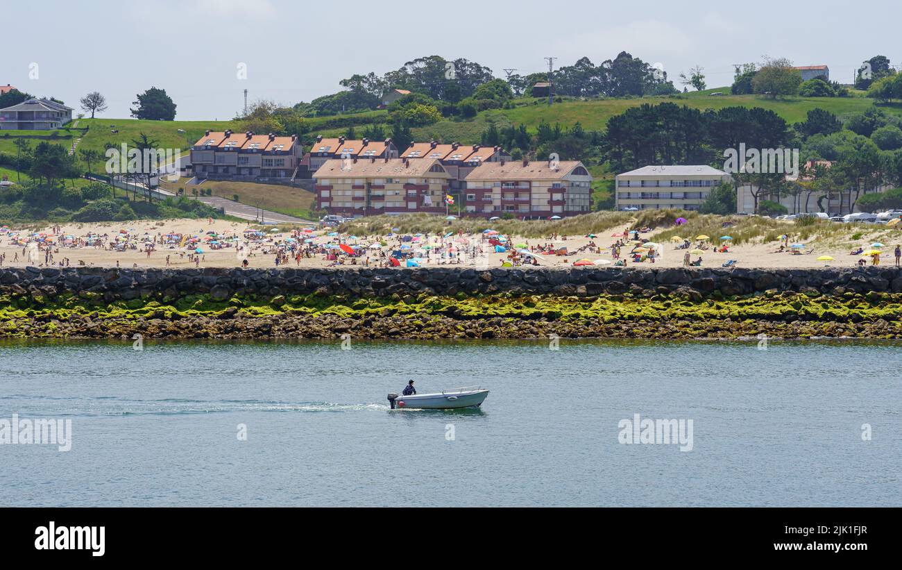 Aerial view of the beach in summer full of people and a small boat passing in front. Suances Santander. Stock Photo