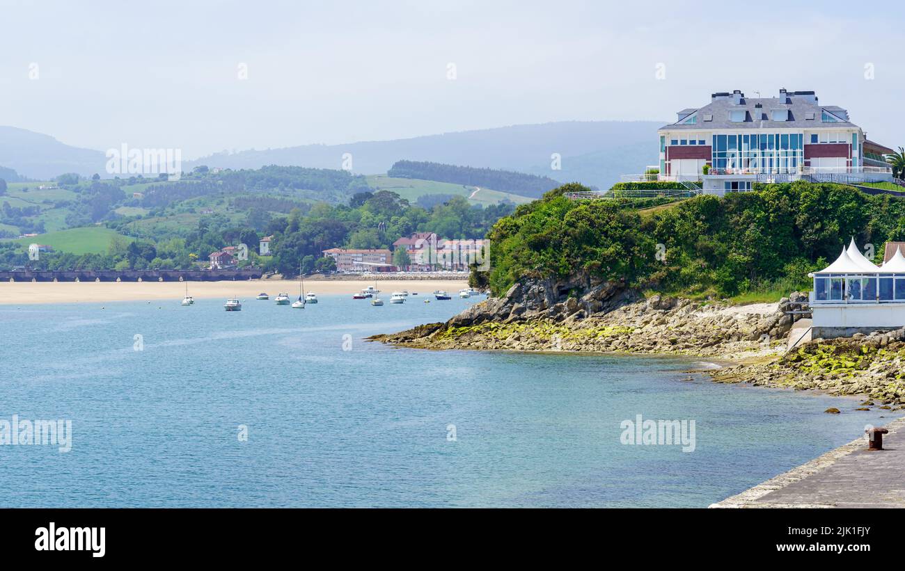 Seascape with area beach, moored boats and green mountains. Suances Santander. Stock Photo