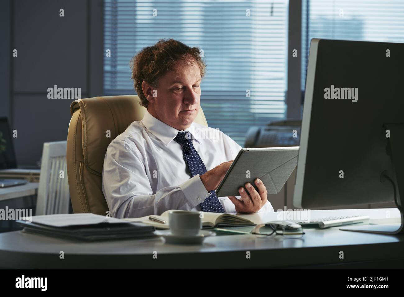 Mature businesman reading information on digital tablet Stock Photo
