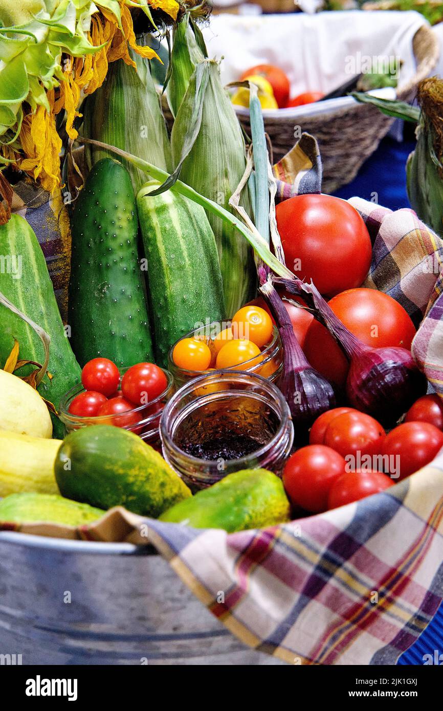 A container of farm fresh tomatoes, onions, cucumbers, and corn on