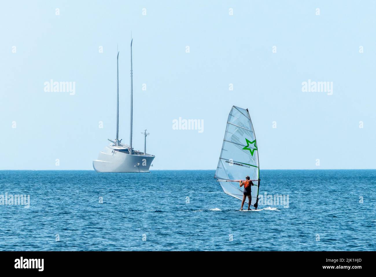 Trieste, Italy, 28 July 2022.  A man windsurfts near the biggest sailing yacht in the world sequestered in the Adriatic port of Trieste. The 530 milli Stock Photo