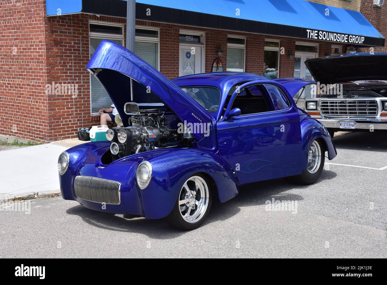 A Vintage Willys Restomod with a 454 Supercharged Engine on display at a car show. Stock Photo