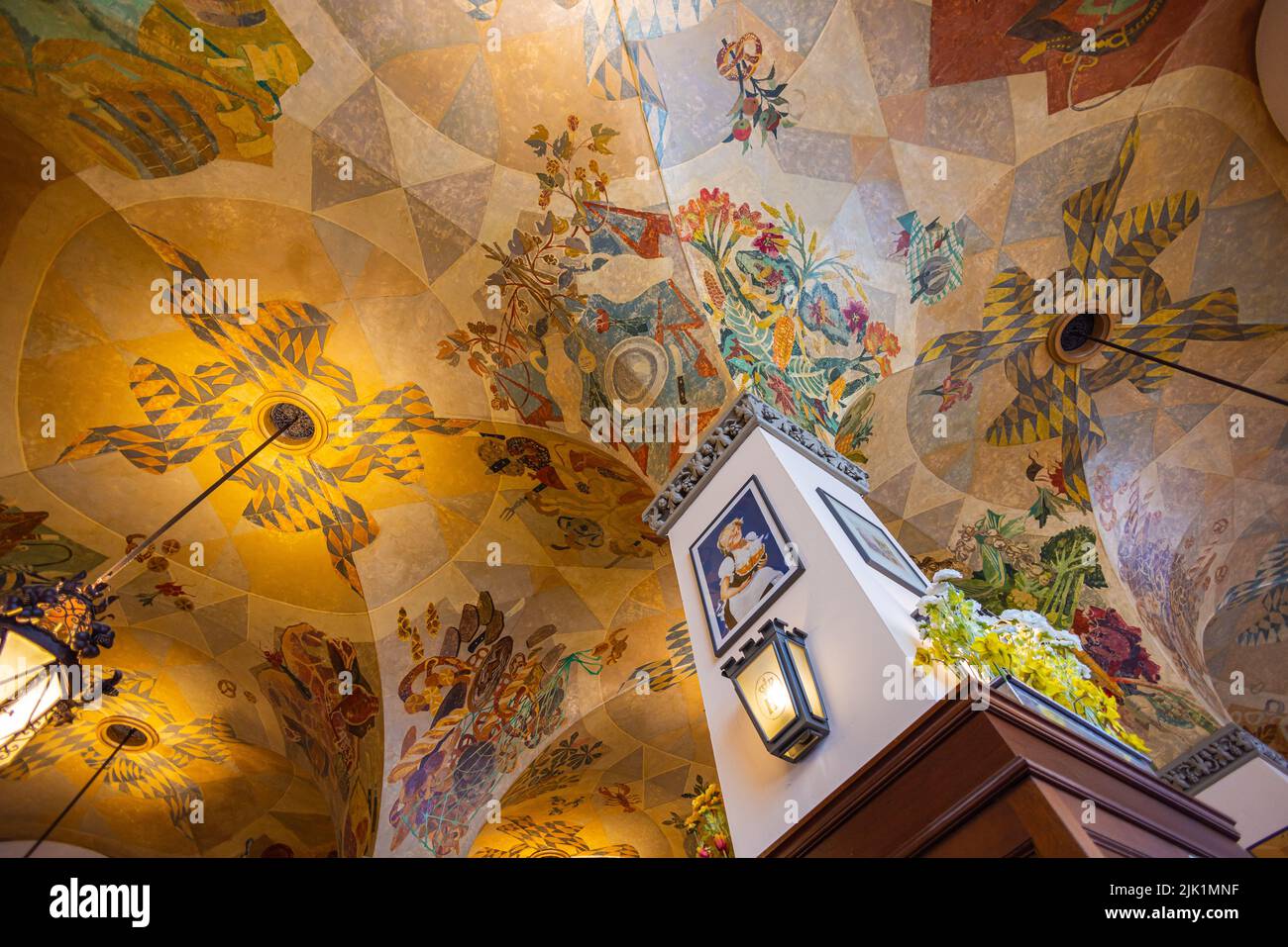 Munich, Germany - July 6, 2022: Inside Hofbräuhaus with detailed traditional ceiling painting. Looking up at the ceiling, past the pillar with old adv Stock Photo
