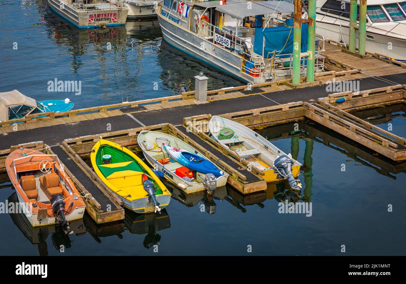 Colorful small boats parked to wooden pier with reflection in a water. Motor boats in marina on a summer day. Nobody, travel photo-Nanaimo BC Canada-J Stock Photo