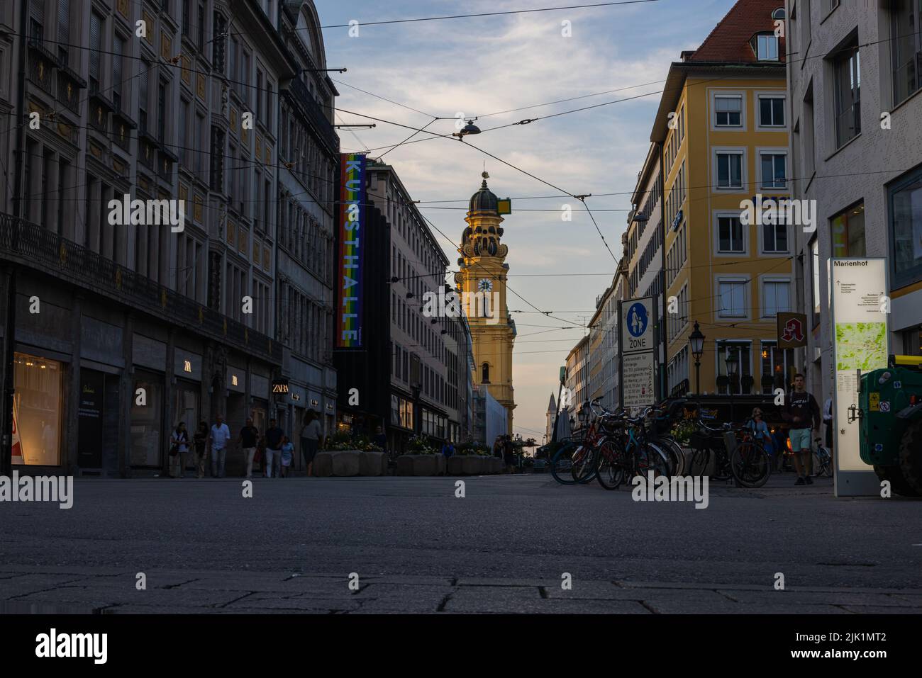 Munich, Germany - July 6, 2022: Low angle street view of Theatinerstrasse overlooking Theatinerkirche at sunset. The church tower or bell tower with i Stock Photo