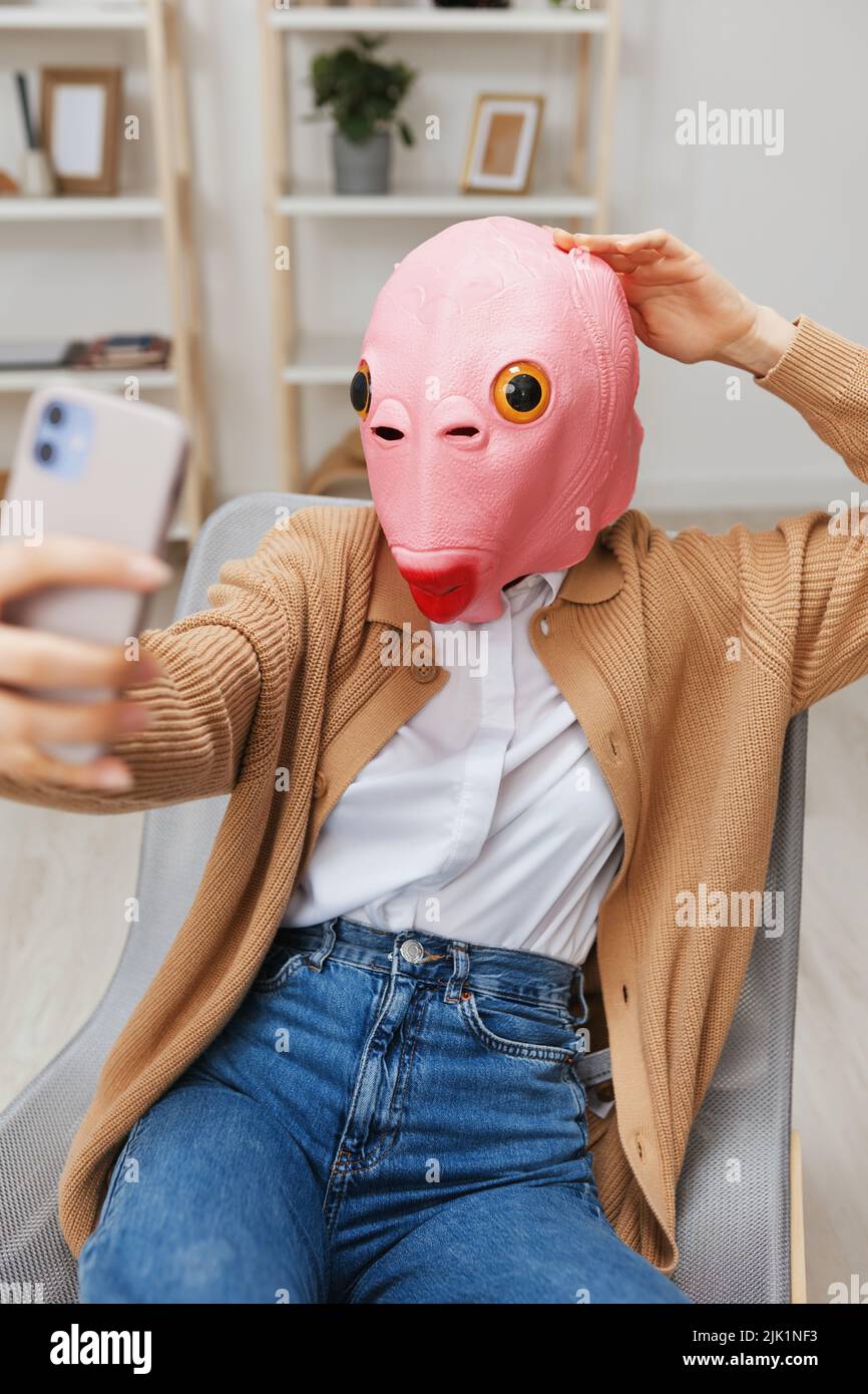 Happy funny blonde lady in pink fish mask warm sweater doing selfie video  call sitting in armchair at modern home interior. Pause from work, take a  Stock Photo - Alamy