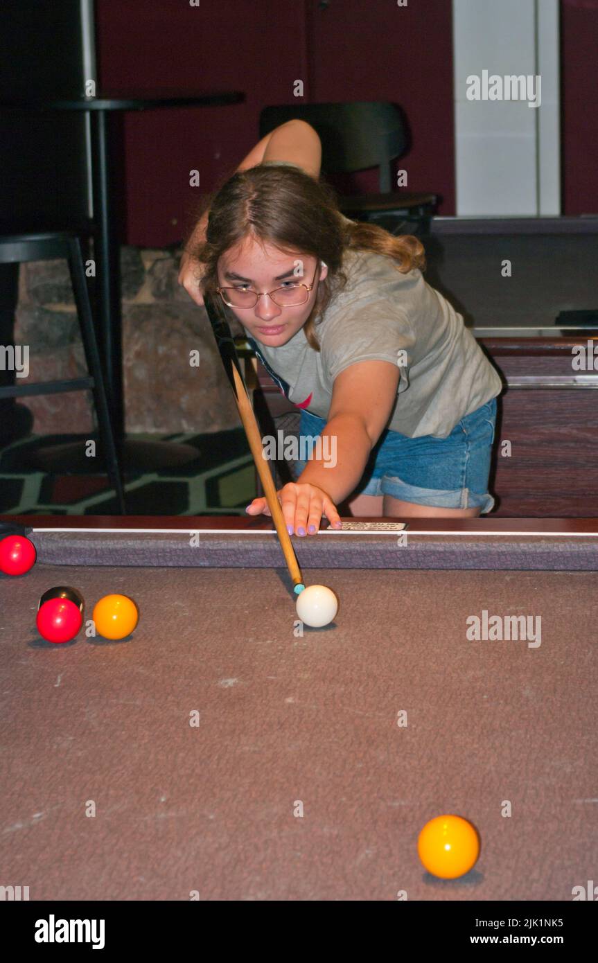 Young Girl Playing Pool Inside a Pool Hall Stock Photo
