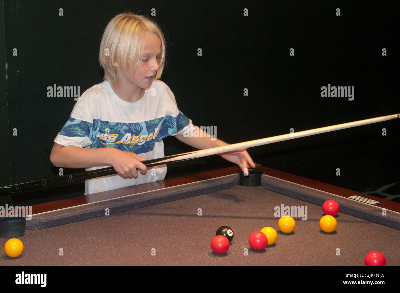 Young Boy Playing Pool Inside a Pool Hall Stock Photo