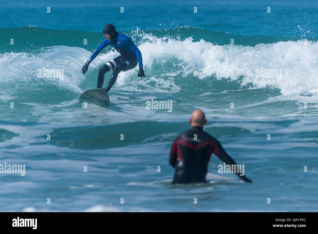 Surfing action as a surfer rides a wave at Fistral in Newquay in Cornwall in the UK. Stock Photo