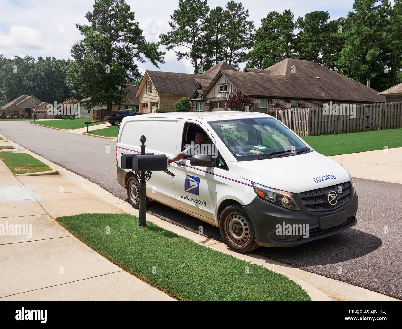 United States Postal Service, USPS, mail carrier in a Post Office vehicle delivering the mail to a residential mailbox in Montgomery Alabama, USA. Stock Photo