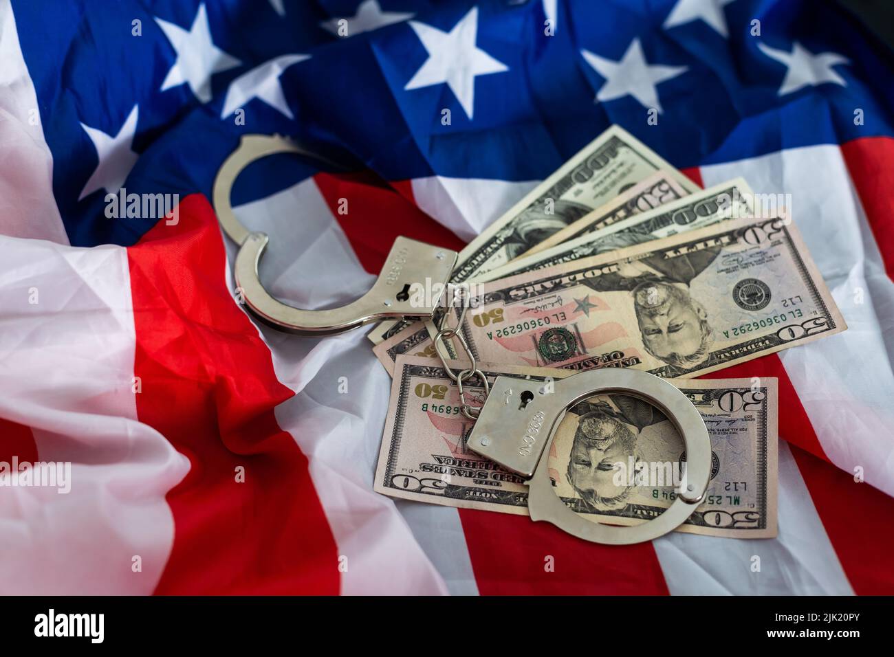 metal handcuff, american dollars cash over flag of USA. Illegal concept. Bribing and corruption Stock Photo