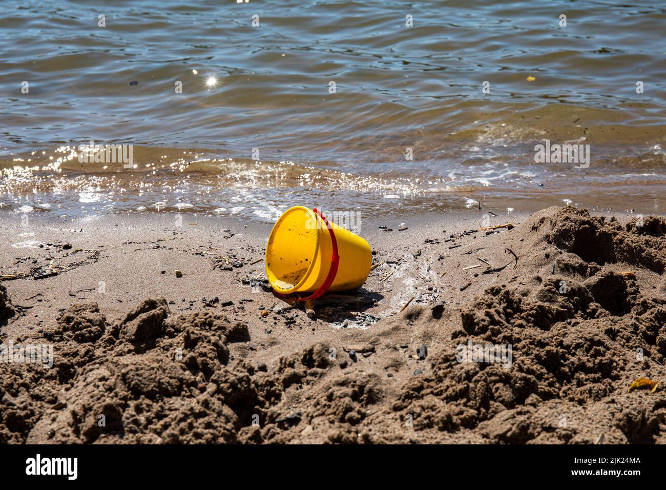 Abandoned plastic beach bucket sand toy on beach Stock Photo