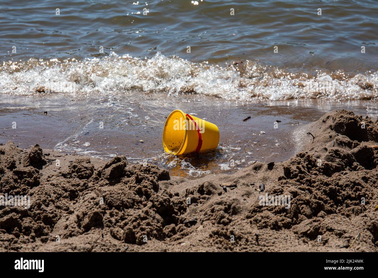 Abandoned yellow plastic beach bucket sand toy on a beach Stock Photo