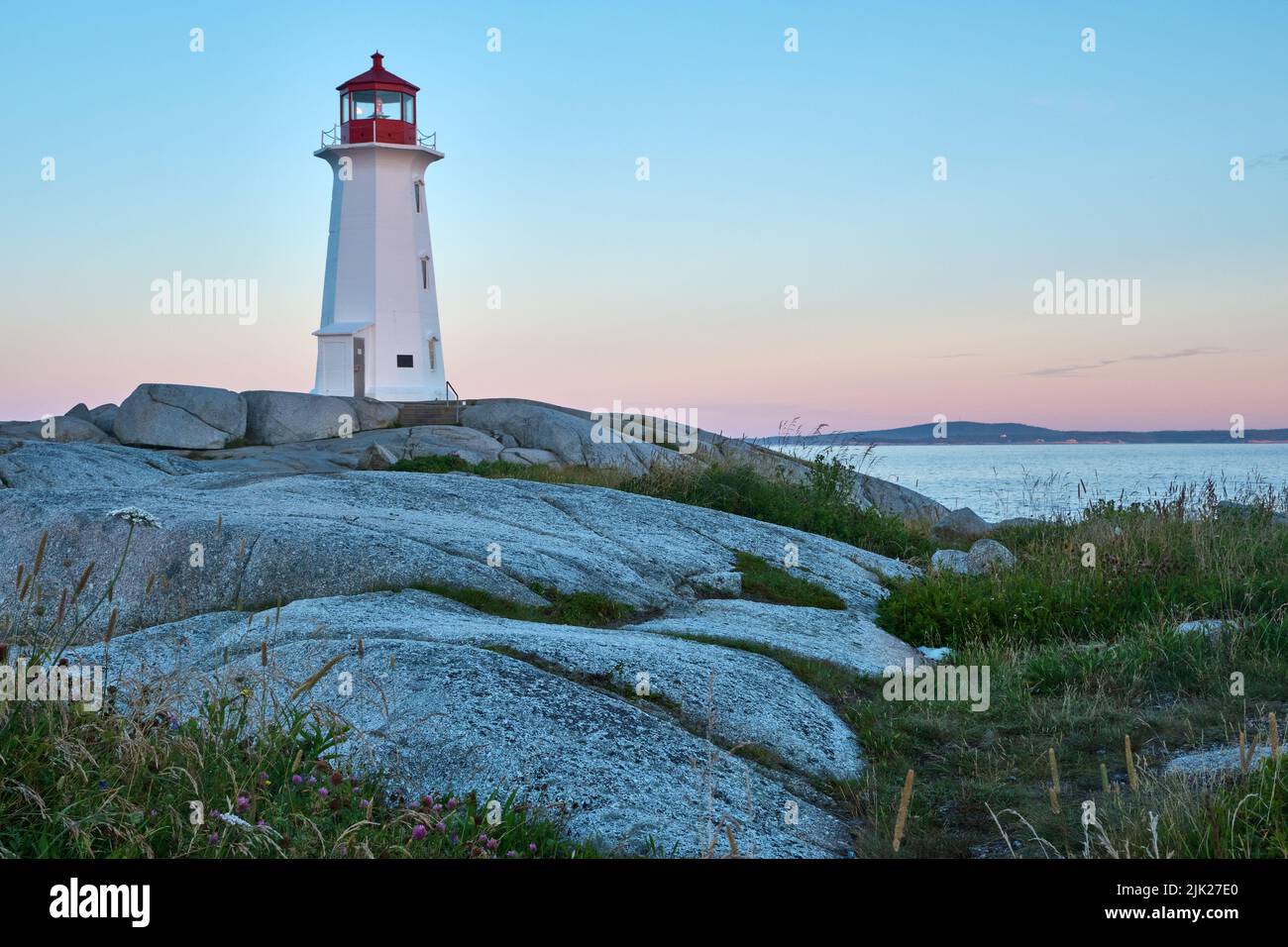 Photograph of the iconic Peggy's Cove lighthouse taken at sunrise on a beautiful summer morning. Stock Photo