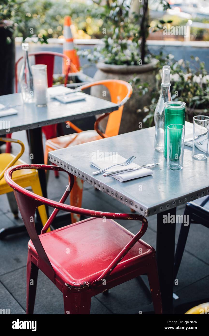 outdoor patio tables with colored metal chairs at restaurant Stock Photo