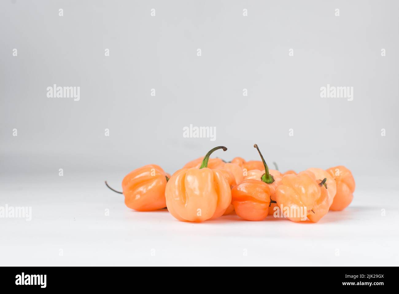 A scotch bonnet pepper with stem on a white background, fresh pepper, orange coral pepper, Nigerian scotch bonnet pepper Stock Photo