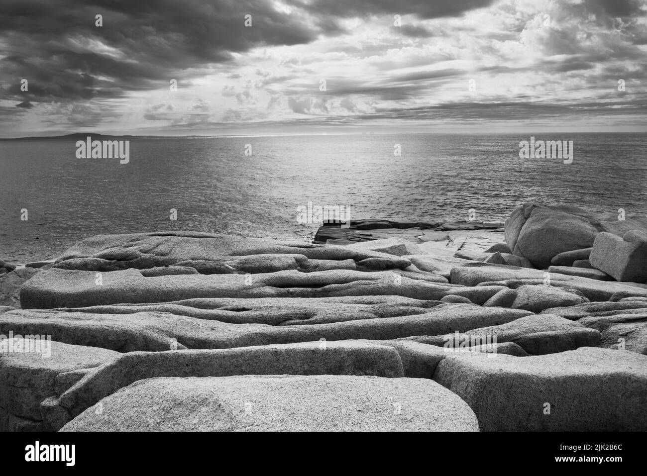 An artsy b&w photograph of the weathered granite boulders looking towards sunrise on the Atlantic Ocean along the coast of Acadia National Park, Mount Stock Photo