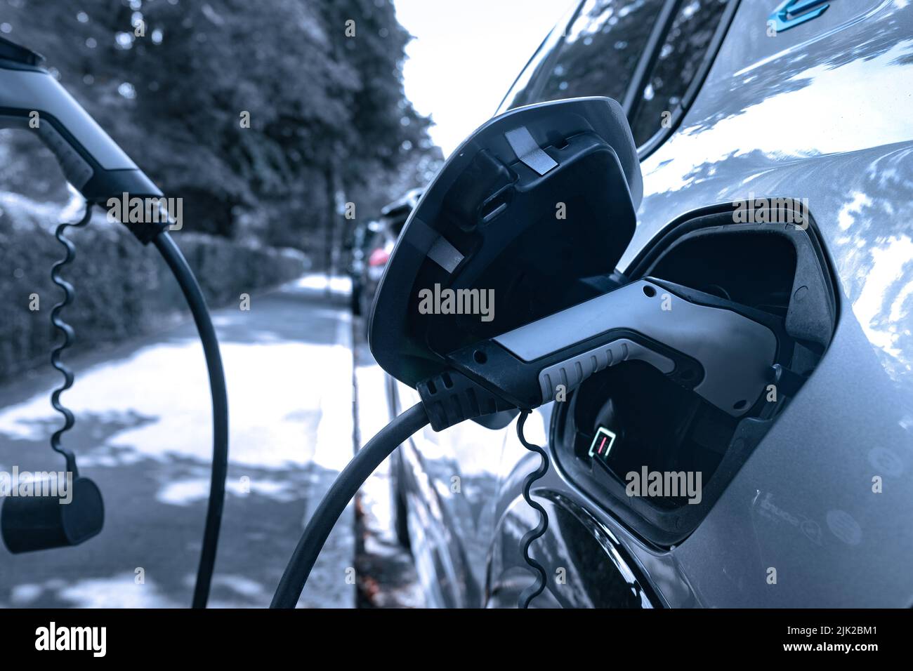 Electric car plugged in and changing on urban city street Stock Photo Alamy