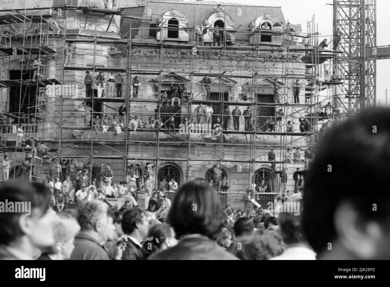 Bucharest, Romania, September 1992. Political rally organized by Romanian Democratic Convention (CDR) before the presidential elections of 1992. Huge crowd in the Revolution Square, with many people standing on the scaffolding used on the buildings damaged in the revolution of 1989. Stock Photo