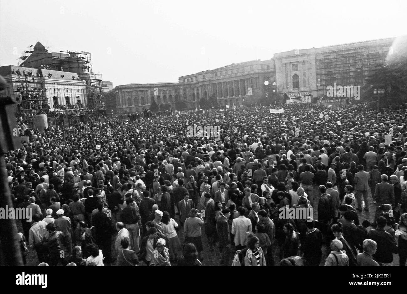 Bucharest, Romania, September 1992. Political rally organized by Romanian Democratic Convention (CDR) before the presidential elections of 1992. Huge crowd in the Revolution Square, with many people standing on the scaffolding used around on the buildings damaged in the revolution of 1989. Stock Photo