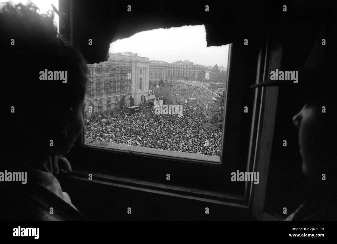 Bucharest, Romania, September 1992. Political rally organized by Romanian Democratic Convention (CDR) before the presidential elections of 1992. Huge crowd in the Revolution Square, with many people standing on the scaffolding used on the buildings damaged in the revolution of 1989. Others were watching from inside some of these buildings. Stock Photo