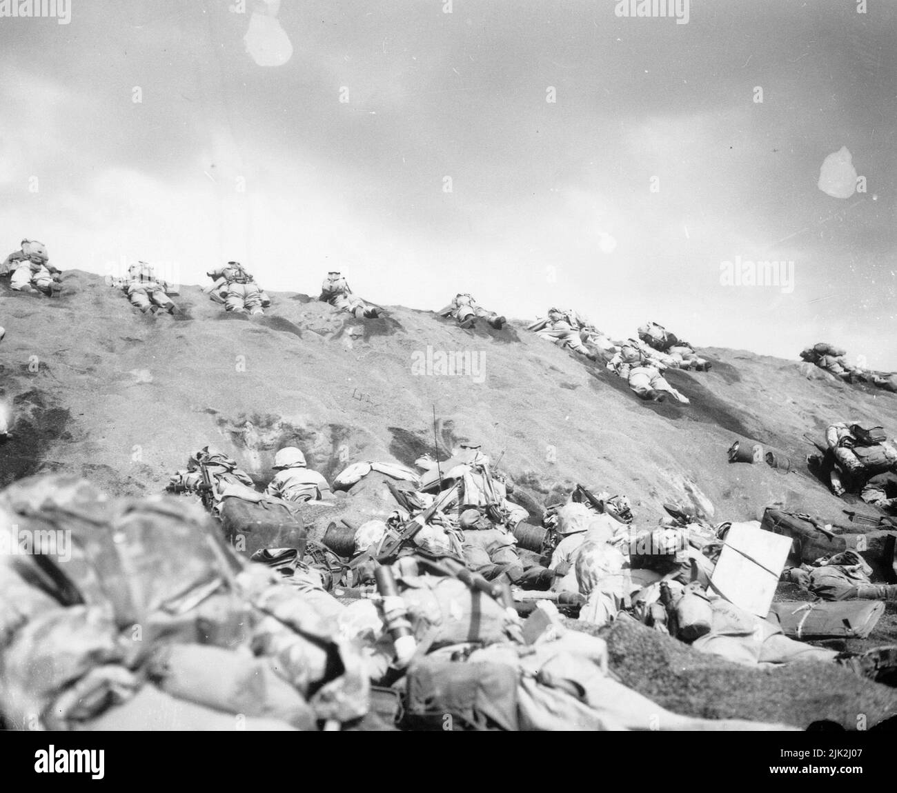 Marines of the 5th Division inch their way up a slope on Red Beach No. 1 toward Surbachi Yama as the smoke of the battle drifts about them. Stock Photo